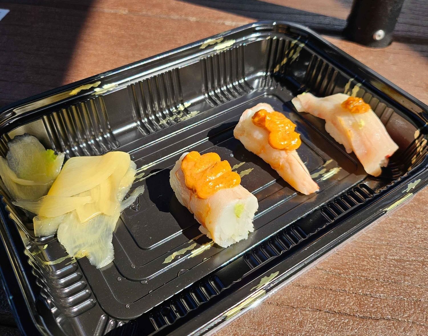 black plastic container with three pieces of sushi